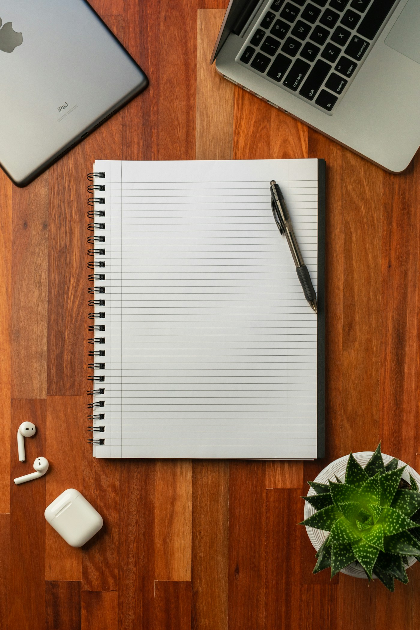 An open notebook and pen on a wooden desk